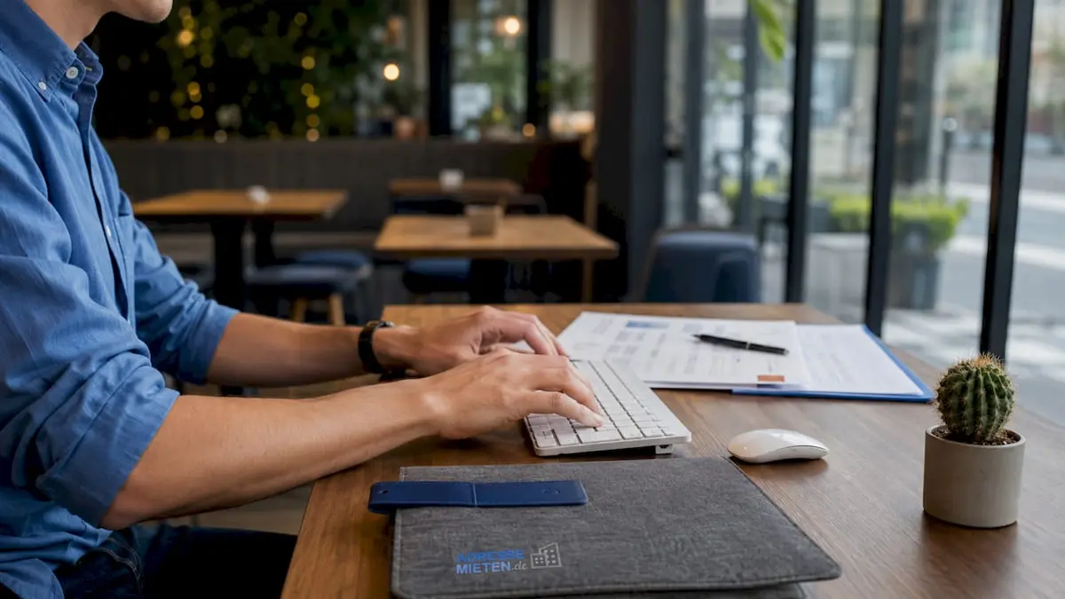 Von oben fotografiert: Hände tippen auf einer Tastatur, daneben liegen Vertragsunterlagen.